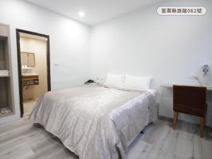 a white bedroom with a bed and a desk at WE Hotel in Miaoli