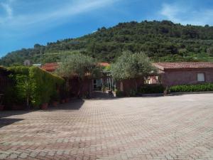 a brick courtyard with trees and a mountain in the background at Abbamala Village in Bosa