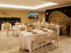 a restaurant with white tables and chairs and a wall at Decollage Estate in Polokwane