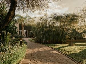 a brick walkway in a park with a bench at Decollage Estate in Polokwane