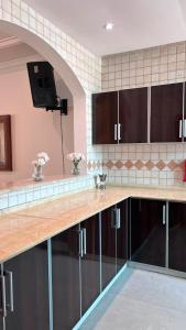 a kitchen with brown cabinets and a tv on the wall at Rose Beach 7 درة العروس in Jeddah
