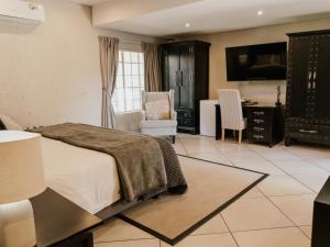 a bedroom with a bed and a desk and a kitchen at Decollage Estate in Polokwane