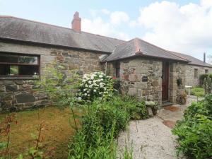 an old stone house with flowers in front of it at Swallow Cottage in Helston
