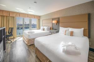 a hotel room with two beds and a television at Coast Lonsdale Quay Hotel in North Vancouver