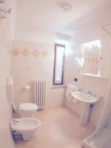 Un baño blanco con inodoro y lavabo. en Albergo Bel Soggiorno, en Fiumalbo