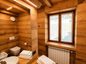 a bathroom with a toilet sink and a window at SkyWood Chalet, Panoramic Mountain and Lake Views in Mello +14 photos