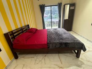 a bed with a red comforter in a room with a window at Golden rays beach stay in Mangalore