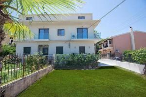 a white house with a fence and a yard at Greenery Luxury Apartment in Potamós