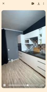 a kitchen with white cabinets and a wooden floor at Kawalerka in Kwidzyn