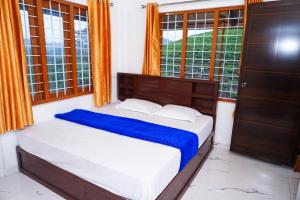 a bedroom with a bed with a blue blanket and windows at River side in Vagamon