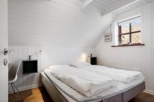 a white bedroom with a large bed and a television at 068-Ringkobing-Hvidbjergvej-4 in Søndervig