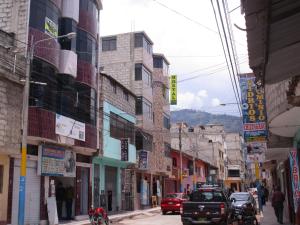een drukke stadsstraat met auto's en gebouwen bij Hostal Arcangel in Abancay