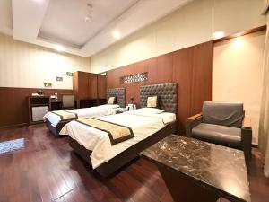 a hotel room with two beds and a chair at Hotel President, Pure Veg in Indore +109 photos