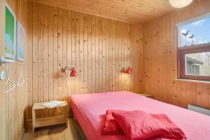 a bedroom with a pink bed in a wooden wall at 30168-Odder-Pouli-Nielsensvej-3 in Odder