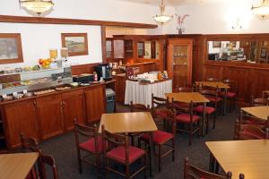 a restaurant with wooden tables and chairs and a counter at Hotel Maria in Ostrava