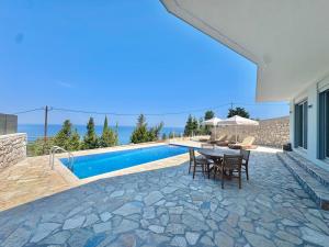 a patio with a table and chairs next to a swimming pool at Vento Villas in Agios Nikitas