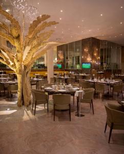a restaurant with tables and chairs and a tree at UNA HOTELS MH Matera in Matera