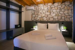 a bedroom with a large bed and a stone wall at Nine Muses Hospitality in Nea Irakleia