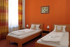 two beds in a room with orange walls at Hotel Maria in Ostrava