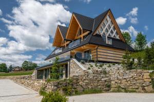 a house with a black roof on top of a stone wall at TatryTop Giewont House Wellness in Kościelisko +95 photos