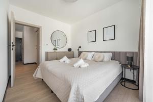 a white bedroom with a large bed and a mirror at Apartament Panorama Pod Dębowcem in Bielsko-Biała