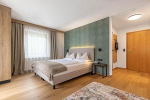 a bedroom with a bed and a green wall at Hotel Garni Romantika in Sankt Leonhard im Pitztal +56 photos