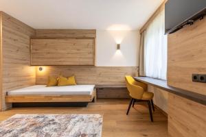 a bedroom with a bed and a desk with a yellow chair at Hotel Garni Romantika in Sankt Leonhard im Pitztal