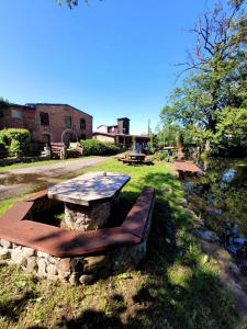 a picnic table and a bench next to a pond at Pensjonat Stary Mlyn Tuczno in Tuczno
