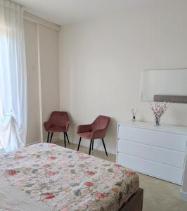 a bedroom with a bed and two chairs and a dresser at Appartamento La Finestra sul Borgo in Santarcangelo di Romagna +8 photos