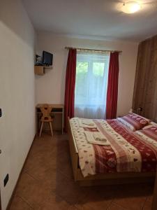 a bedroom with a bed and a window with red curtains at Roda de Vael in Moena