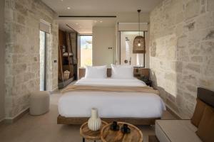 ein Schlafzimmer mit einem großen weißen Bett und einem Tisch in der Unterkunft Socrates Hotel & Villas Malia Beach in Malia