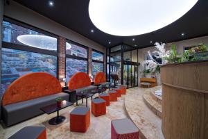 eine Lobby mit orangefarbenen Stühlen, Tischen und Fenstern in der Unterkunft La Terrasse in Douai