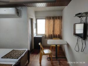 a small room with a bed and a table and a television at Hotel heena in Bīr