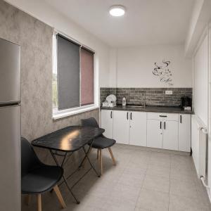 a kitchen with white cabinets and a table and chairs at Nicolle Elite Apartment in Piteşti