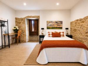a bedroom with a large bed and a stone wall at O Rincón de Esther in Vedra