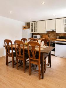 a kitchen with a wooden table and wooden chairs at O Rincón de Esther in Vedra