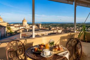 a table with a plate of food on a balcony at Panorama Suites Noto - Adults Only in Noto