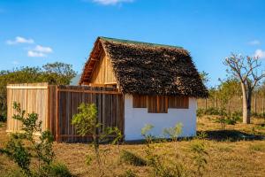a small house with a thatched roof and a fence at Casa Lantana in Antsiranana