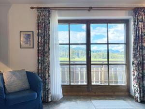 a living room with a large window and a blue couch at Sonnenhof Seeg 01 in Seeg