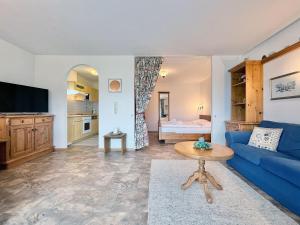 a living room with a blue couch and a tv at Sonnenhof Seeg 01 in Seeg
