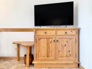 a television on top of a wooden cabinet with a table at Sonnenhof Seeg 01 in Seeg