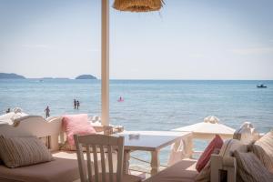 a beach with a table and chairs and the ocean at CP Seafront Suites in Laganas