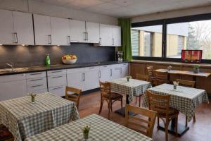eine Küche mit zwei Tischen und eine Küche mit weißen Schränken in der Unterkunft Vintage HOTEL S-Weilimdorf in Stuttgart-Weilimdorf