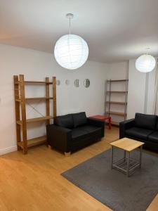 a living room with two black couches and a table at Central 2 bed large apt M1 area in Manchester