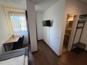 ein Zimmer mit einem Schreibtisch und einem Fernseher an der Wand in der Unterkunft Vintage HOTEL S-Weilimdorf in Stuttgart-Weilimdorf