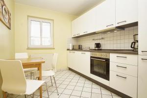 a kitchen with white cabinets and a table and chairs at Haus Rügen Ferienwohnung 08 mit Sauna- und Schwimmbadnutzung im AHOI Sellin in Göhren