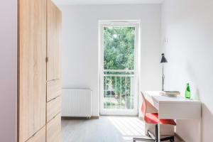 a white kitchen with a desk and a window at HomeKoko Apartments in Katowice
