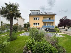 a yellow house with a palm tree in a yard at Ferienwohnung Roller in Endingen