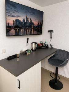 a desk with a chair and a television on a wall at NEU! Fly & Stay Residence Frankfurt Airport Kelsterbach in Kelsterbach