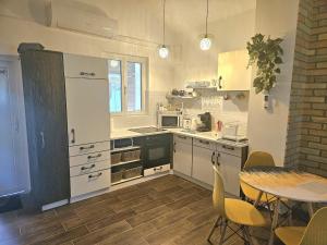 a kitchen with white cabinets and a table with chairs at Marina Cottage in Enying